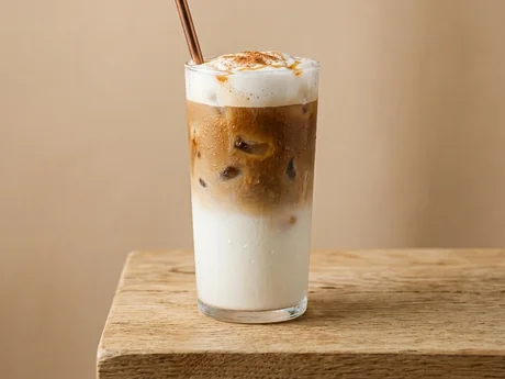 Café helado con crema, canela y caramelo en vaso alto